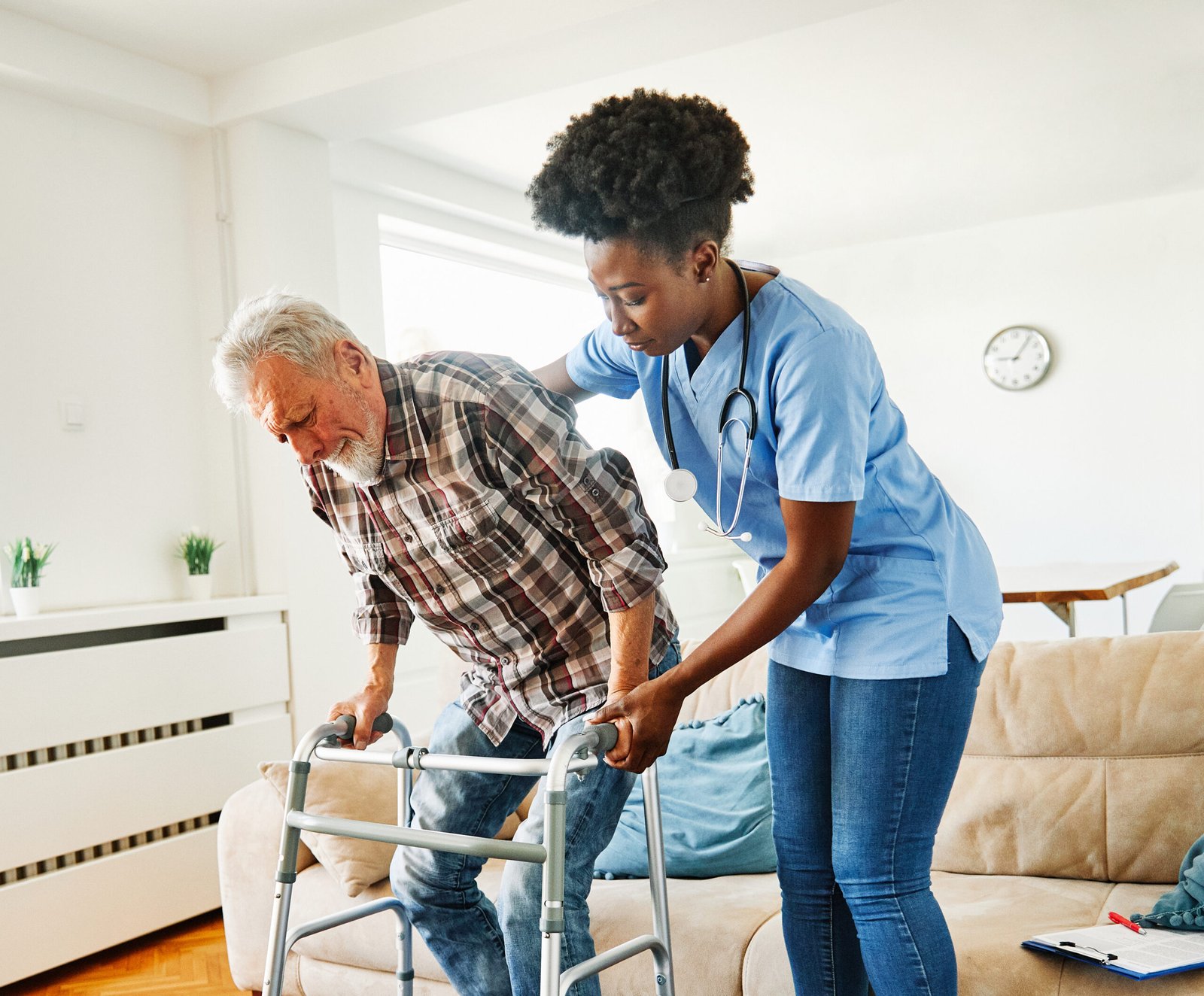 Old man with carer assisting him to walk with the help of a walker